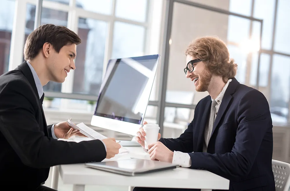 2 men sitting at a table having a conversation